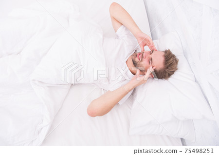 Migraine headaches. Handsome man relaxing in bed. Migraine headaches. Handsome man relaxing in bed. 75498251