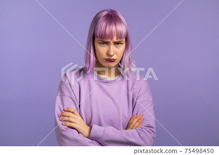 Angry offended woman with dyed purple hair keeping arms crossed and staring at camera with sceptical 75498450