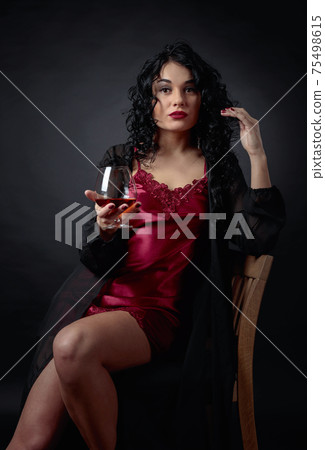 Portrait of attractive brunette with glass of brandy on a black background. Portrait of attractive brunette with glass of brandy on a black background. 75498615