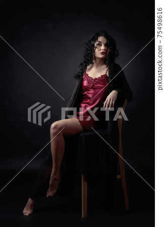 Young beautiful woman with long curly hair in negligee. Young beautiful woman with long curly hair in negligee. 75498616