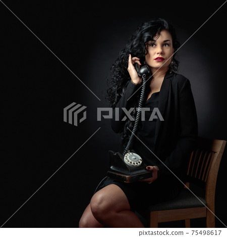 Portrait of attractive brunette with old phone on a black bacground. Portrait of attractive brunette with old phone on a black bacground. 75498617