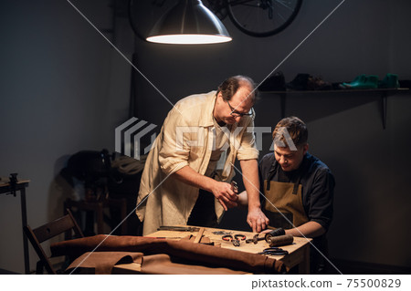 father and son prepare a gift for mother, enthusiastically make shoes in a Shoe shop. 75500829