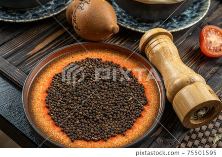Heap of hot black pepper in bowl on a wooden table  75501595