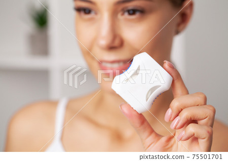 Cheerful brunette woman using dental floss in bathroom Cheerful brunette woman using dental floss in bathroom 75501701