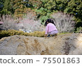 Back view of a girl sitting and playing in abundant nature 75501863