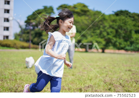 Little girl walking a dog 75502523