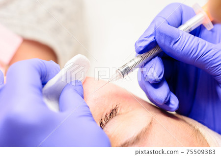 Milium on the face, removal of milia with a syringe in cosmetology. 75509383