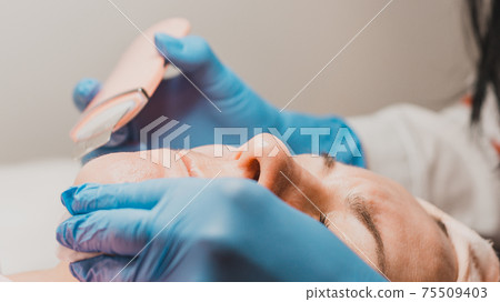 Moisturizing the face and removing keratinized old skin, the beautician uses ultrasound with microvibrations. 75509403