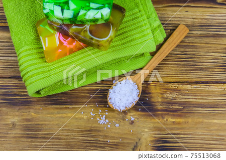 Set of handmade soap bars, sea salt and towel on wooden background. Top view. SPA concept Set of handmade soap bars, sea salt and towel on wooden background. Top view. SPA concept 75513068
