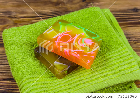 Set of handmade soap bars and towel on wooden background Set of handmade soap bars and towel on wooden background 75513069