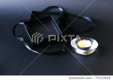 Black ribbon, burning candle, box, frame on a dark background, mourning concept, postcard 75513658