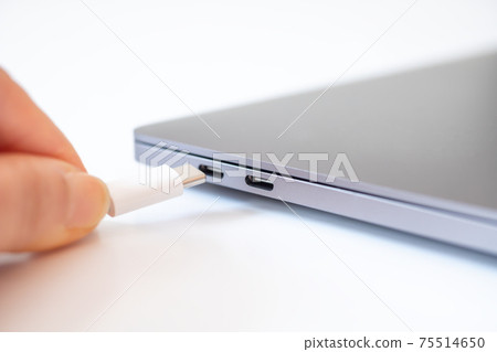 Female hand connecting a computer and a cable [white background] 75514650