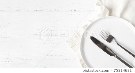 An empty plate and cutlery on a white table. An empty plate and cutlery on a white table. 75514651