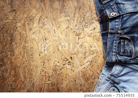 Denim jeans on chipboard wooden background texture Denim jeans on chipboard wooden background texture 75514935