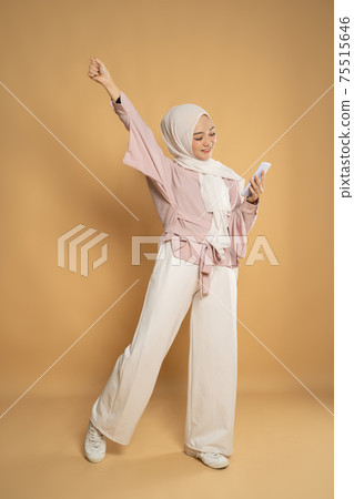 muslim woman euphoric raising arm on studio shot 75515646