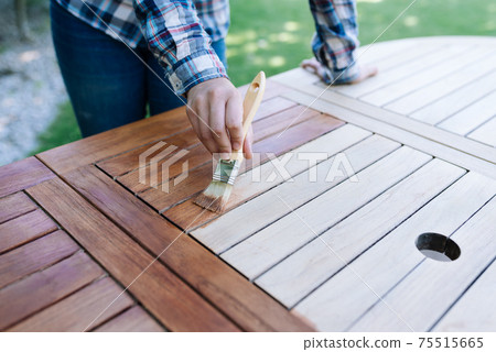 renovation of a garden table with a paintbrush and oil by a young girl renovation of a garden table with a paintbrush and oil by a young girl 75515665