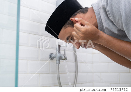 Young Muslim man perform ablution wudhu before prayer at home Young Muslim man perform ablution wudhu before prayer at home 75515712