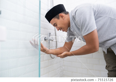 Young Muslim man perform ablution wudhu before prayer at home Young Muslim man perform ablution wudhu before prayer at home 75515726
