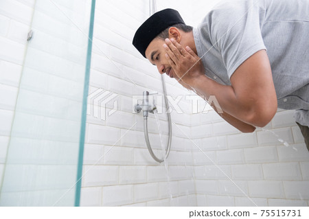Young Muslim man perform ablution wudhu before prayer at home 75515731