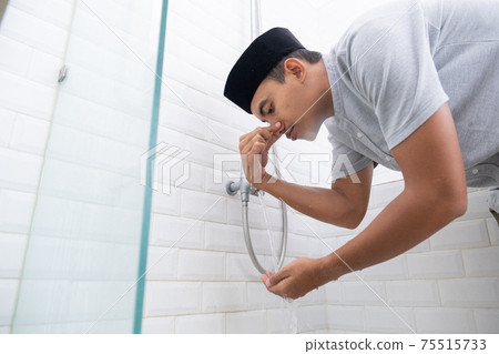 Young Muslim man perform ablution wudhu before prayer at home 75515733