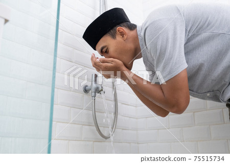 Young Muslim man perform ablution wudhu before prayer at home 75515734