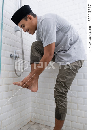 Young Muslim man perform ablution wudhu before prayer at home 75515737