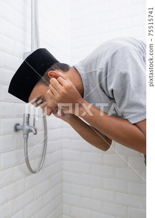 Young Muslim man perform ablution wudhu before prayer at home Young Muslim man perform ablution wudhu before prayer at home 75515741