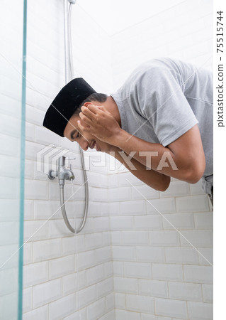 Young Muslim man perform ablution wudhu before prayer at home 75515744