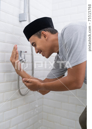 Young Muslim man perform ablution wudhu before prayer at home 75515768