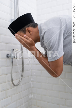 Young Muslim man perform ablution wudhu before prayer at home Young Muslim man perform ablution wudhu before prayer at home 75515770