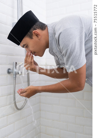 Young Muslim man perform ablution wudhu before prayer at home 75515772