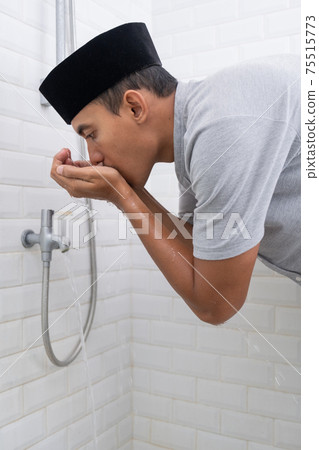Young Muslim man perform ablution wudhu before prayer at home 75515773