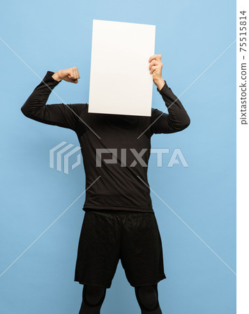 Young man in black attire with blank sheet of paper isolated on blue background. Young man in black attire with blank sheet of paper isolated on blue background. 75515814