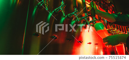 Close-up beer pumps taps in pub or bar in multicolored neon light. 75515874