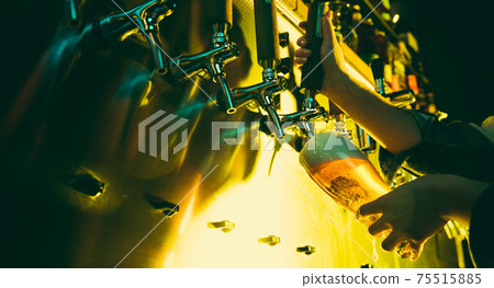 Hands of female barman pouring a cold lager beer from tap to glass in neon light 75515885