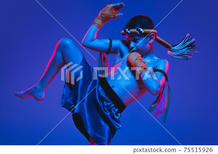 Young boy thai boxer training over blue background in neon light. Young boy thai boxer training over blue background in neon light. 75515926