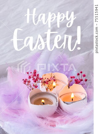 HAPPY EASTER lettering greeting card text. Composition of White egg shell with candle inside. Candle light. Bright easter decorations with bird feathers. Pastel colors. 75515941