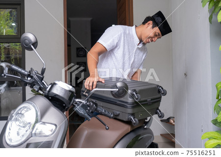male muslim pack his suitcase on his motorbike getting ready to travel during eid mubarak male muslim pack his suitcase on his motorbike getting ready to travel during eid mubarak 75516251