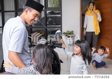 muslim asian father going back home from work being welcome by his family at a front door muslim asian father going back home from work being welcome by his family at a front door 75516268