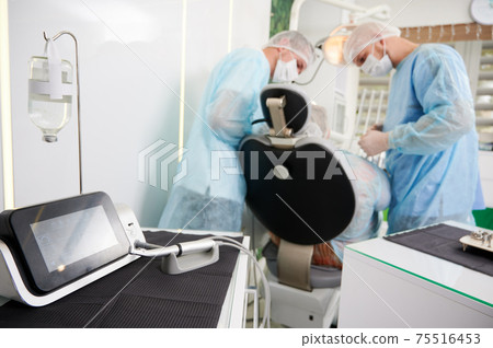 Dentists using dental implant machine in modern dental office. 75516453