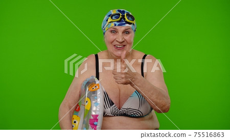 Senior woman tourist in swimsuit bra, swim goggles with swimming ring asking to follow, join Senior woman tourist in swimsuit bra, swim goggles with swimming ring asking to follow, join 75516863