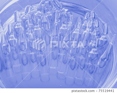 Glass medical ampoule vial for injection. Medicine is liquid sodium chloride with of aqueous solution in ampulla. Close up. Bottles ampule multicolor. Glass medical ampoule vial for injection. Medicine is liquid sodium chloride with of aqueous solution in ampulla. Close up. Bottles ampule multicolor. 75519441