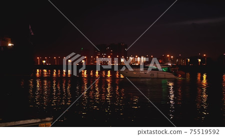 Luxurious modern private yacht and boat at the pier at night. Colorful lights of city glow shine reflected in water wave at nighttime. Luxurious modern private yacht and boat at the pier at night. Colorful lights of city glow shine reflected in water wave at nighttime. 75519592