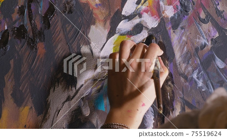 Artist designer draws an eagle on the wall. Craftsman decorator paints a picture with acrylic oil color brush. Close-up dark magic cinematic look. 75519624