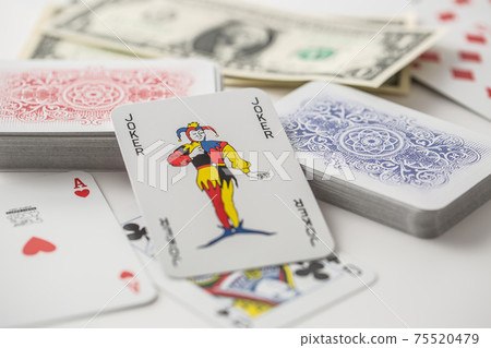 Joker card in the center of various playing cards turned both ways 75520479