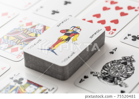 Joker on the pile of cards surrounded by various other playing cars 75520481