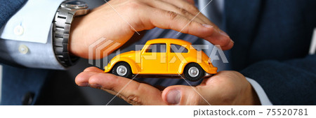 Male arm in suit and tie cover yellow toy car Male arm in suit and tie cover yellow toy car 75520781