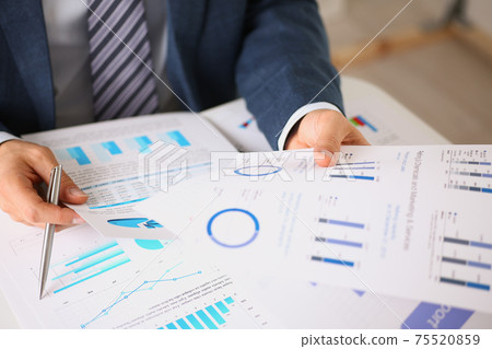 Male hands hold documents with financial statistics Male hands hold documents with financial statistics 75520859