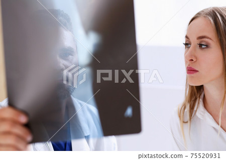Mature male doctor hold in arm and look at xray photography 75520931