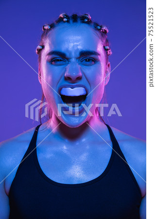 Close-up portrait of athletic girl MMA fighter isolated on blue background 75521523